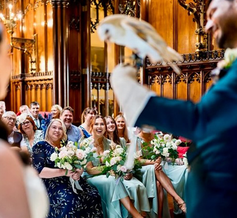 wedding ceremony with guests watching a falconry display featuring a barn owl and floral decorations highlighting the special event throughout the 24 hour festive day